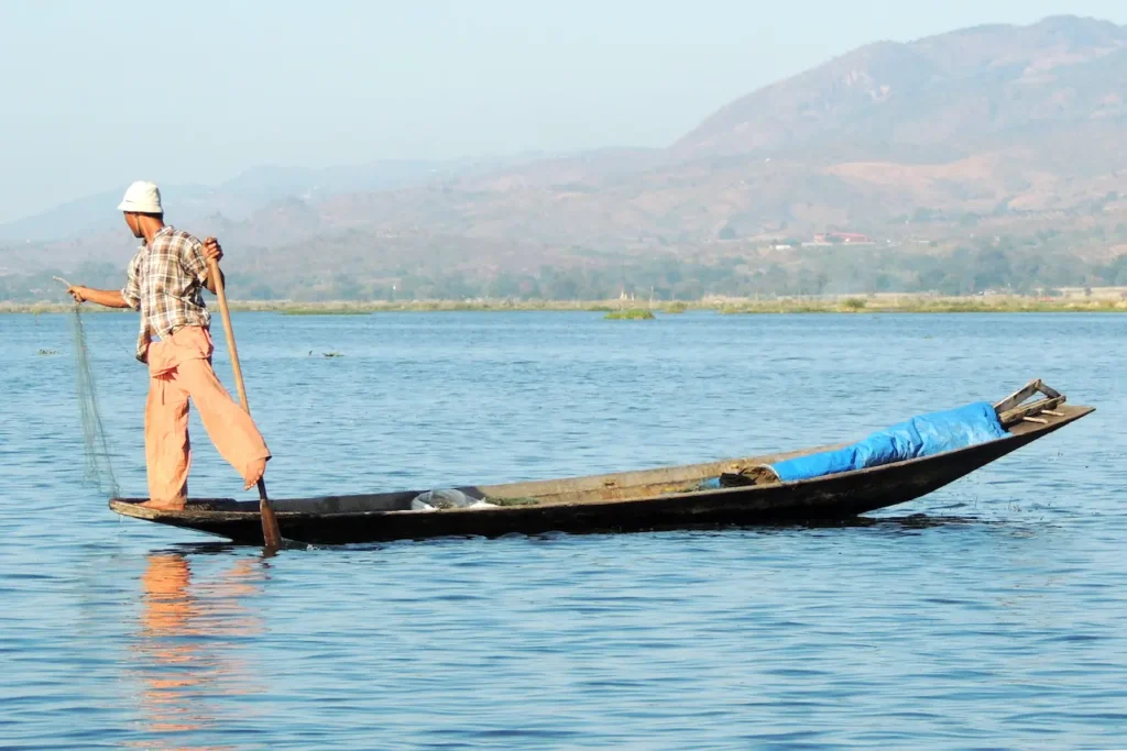 Fisherman Holding a Net and Using One Leg for Rowing