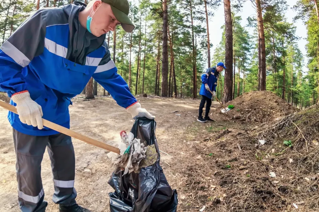 Man in Overalls Collects Garbage and Waste in Forest